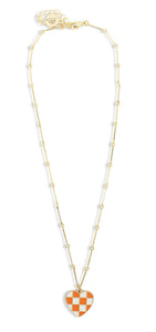 Dainty gold chain necklace featuring an orange and white checkered heart pendant by Bourbon and Boweties.
